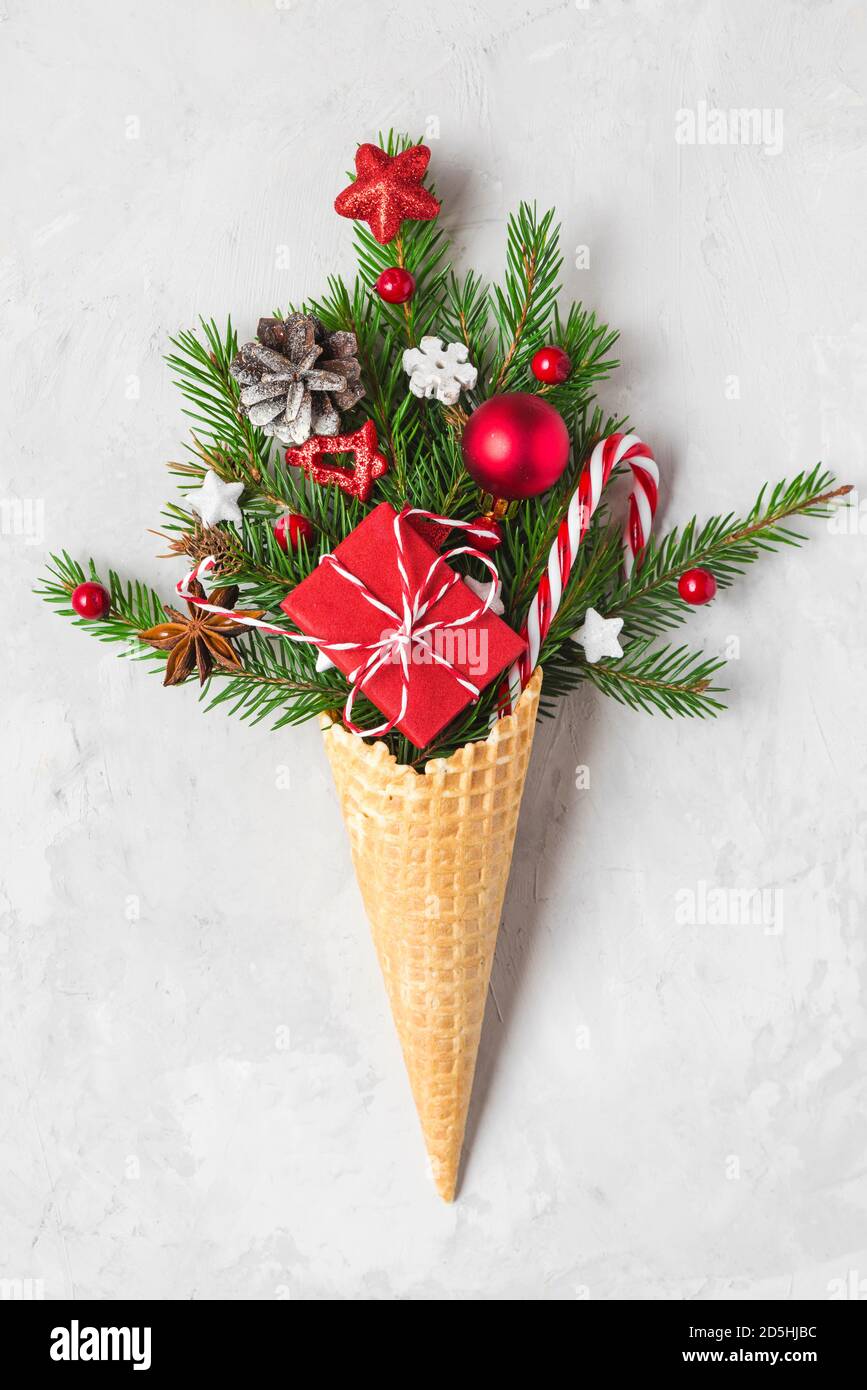 Decorazioni natalizie, abeti, fiocchi di neve, scatola regalo e caramelle nel cono gelato waffle. Concetto di Natale minimo. Disposizione piatta. Orientamento verticale Foto Stock