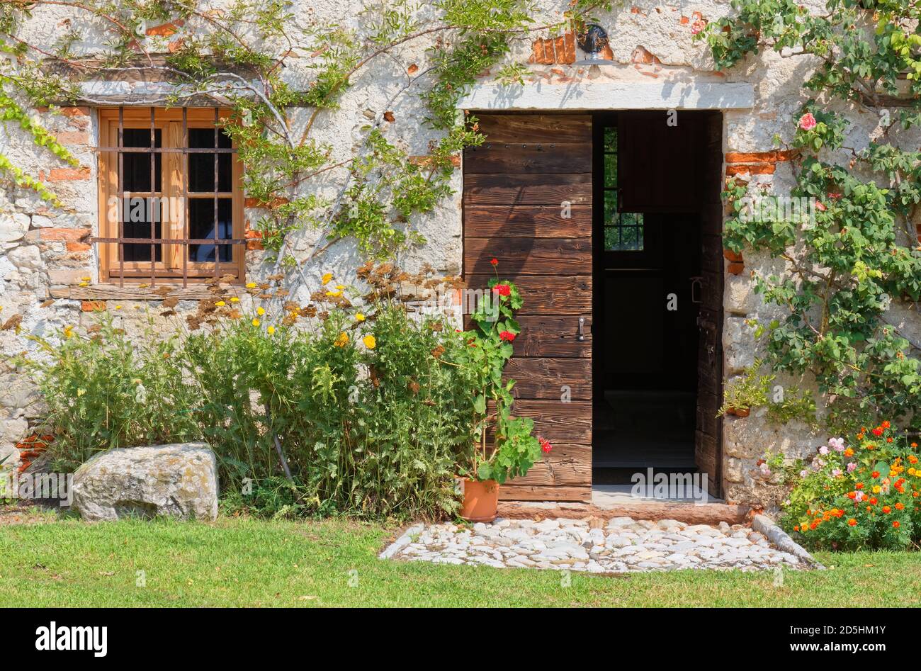 Esterno di un vecchio edificio rurale tradizionale decorato con piante e fiori Foto Stock