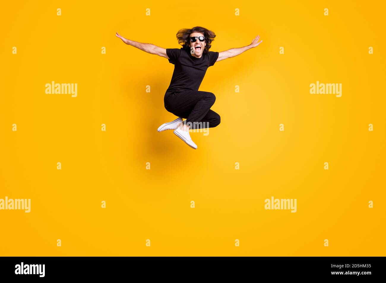 Ritratto a lunghezza intera della taglia del corpo dell'uomo che salta alto che indossa nero abito casual sunglass gridante isolato su colore giallo brillante sfondo Foto Stock