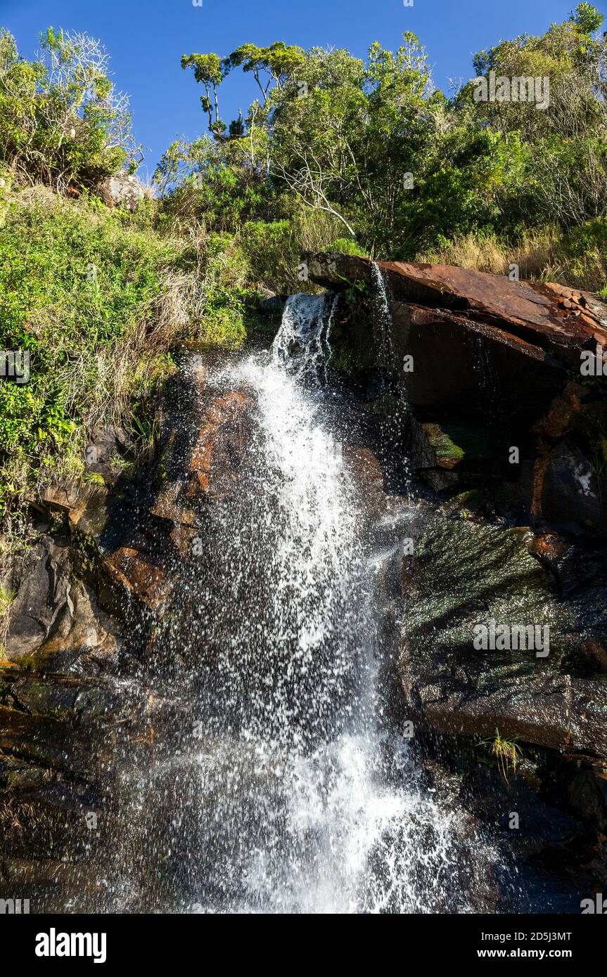 Cascata di Mato Limpo circondata da vegetazione verde e con l'acqua cristallina che scorre e spruzzi sopra le rocce. Cunha, San Paolo - Brasile. Foto Stock