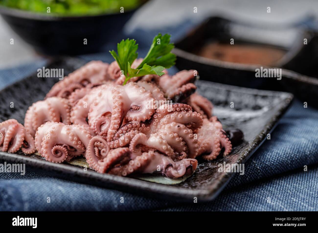 Tradizionale giapponese o concetto di pesce. Mini polpo bollito delizioso e sano e insalata di wakame o alghe con salsa di soia e limone serviti con Foto Stock