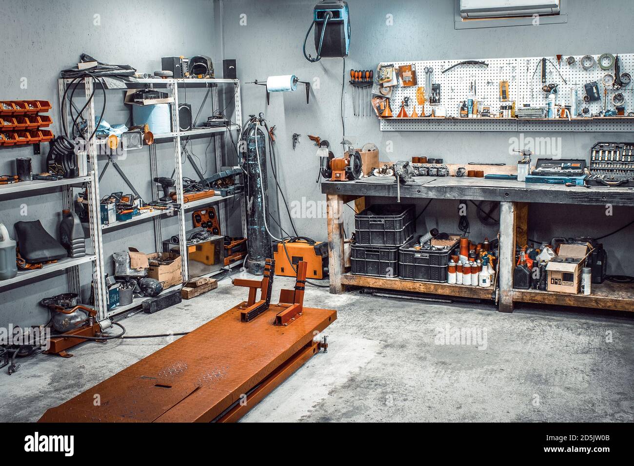 Garage, area di servizio per smontaggio, riparazione moto, stazione di  servizio auto. All'interno dell'officina con ampio banco da lavoro,  scaffalature, motoelevatore, anche Foto stock - Alamy