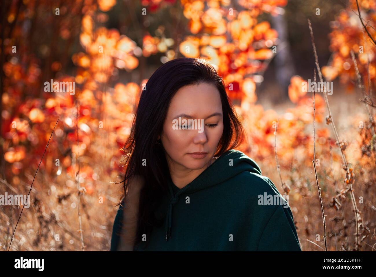 Ritratto della giovane donna sorridente asiatica che guarda giù al terreno in autunno foresta Foto Stock