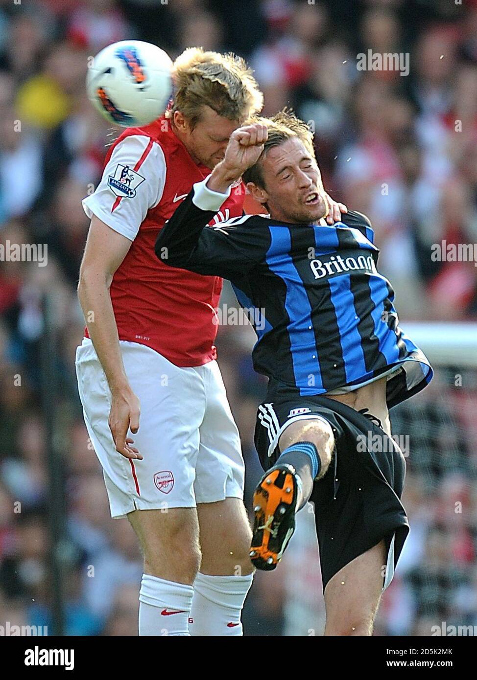 Peter Crouch di Stoke City (a destra) e Arsenal's per Mertesacker (a sinistra) combatti per la palla in aria Foto Stock