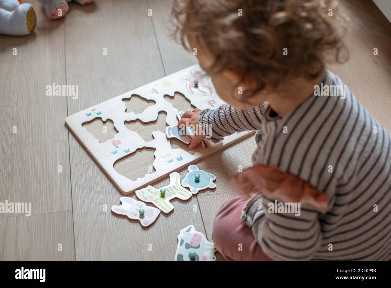 bambino di 17 mesi che gioca con un puzzle di legno, forme adattate di animali Foto Stock