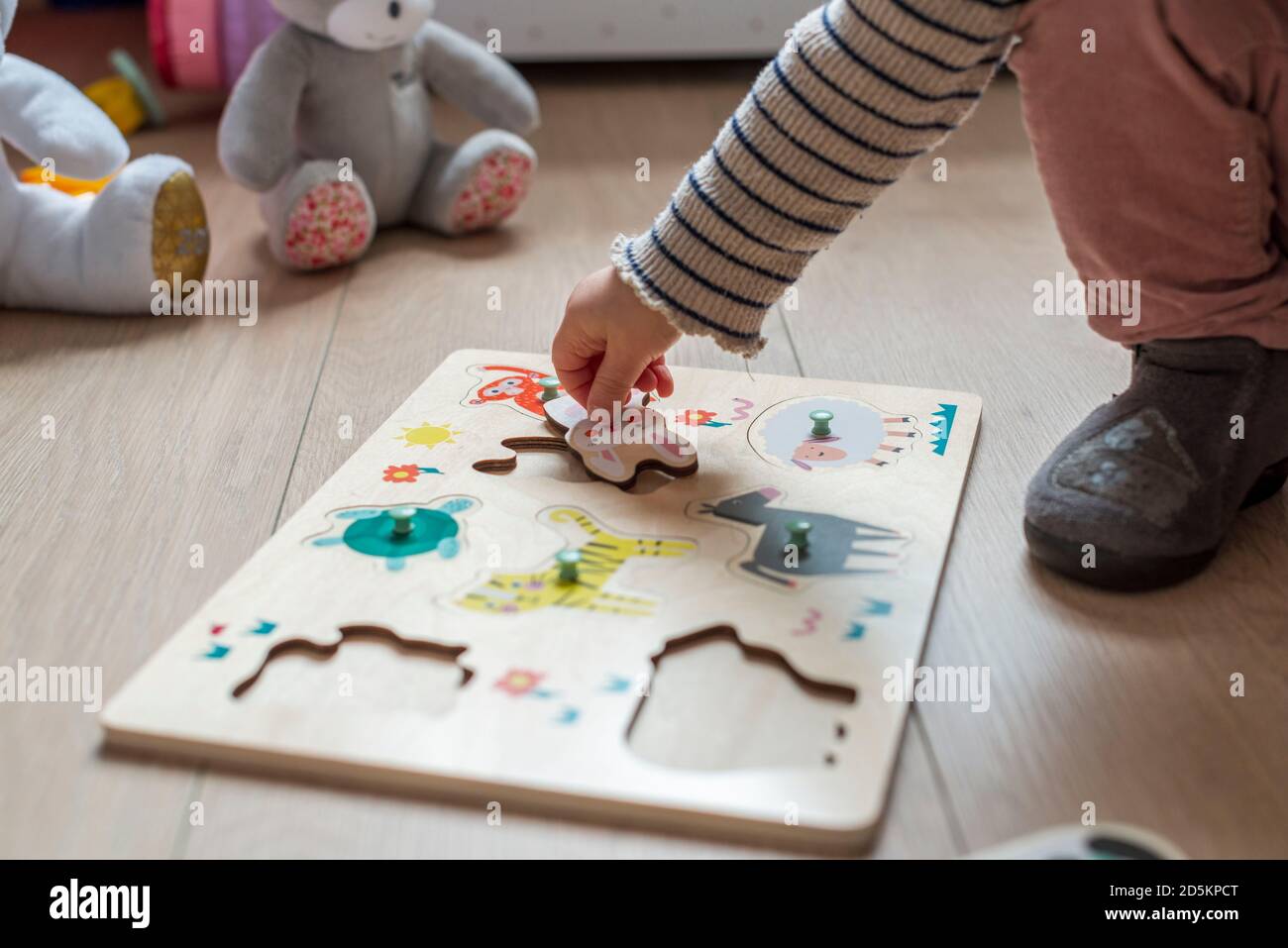 bambino di 17 mesi che gioca con un puzzle di legno, forme adattate di animali Foto Stock
