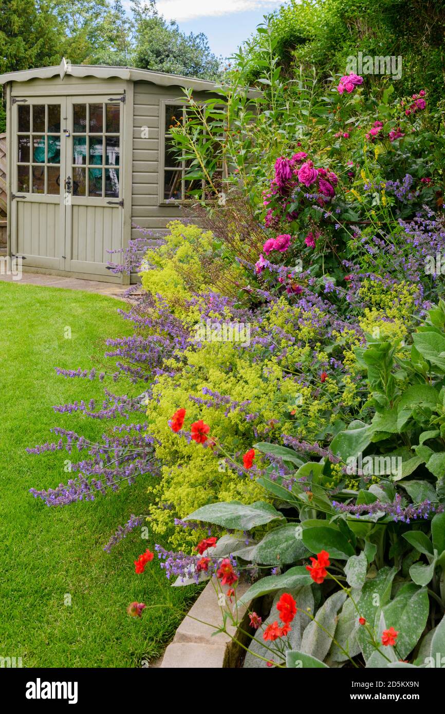 Giardino privato paesaggistico (design contemporaneo, fiori estivi colorati, piante di confine e arbusti, capannone, prato) - Yorkshire, Inghilterra, Regno Unito. Foto Stock