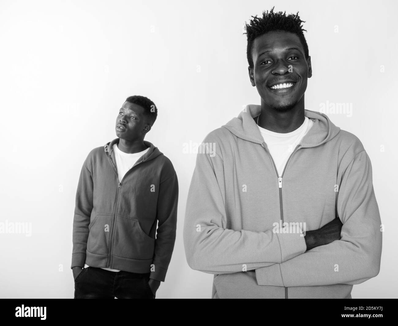 Felice giovane africano sorridente con le braccia incrociate e uno amico che pensa alla schiena Foto Stock