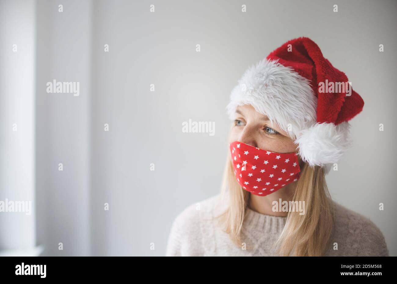 Giovane, bella donna con maschera Corona e cappellino di Natale è in attesa di natale Foto Stock