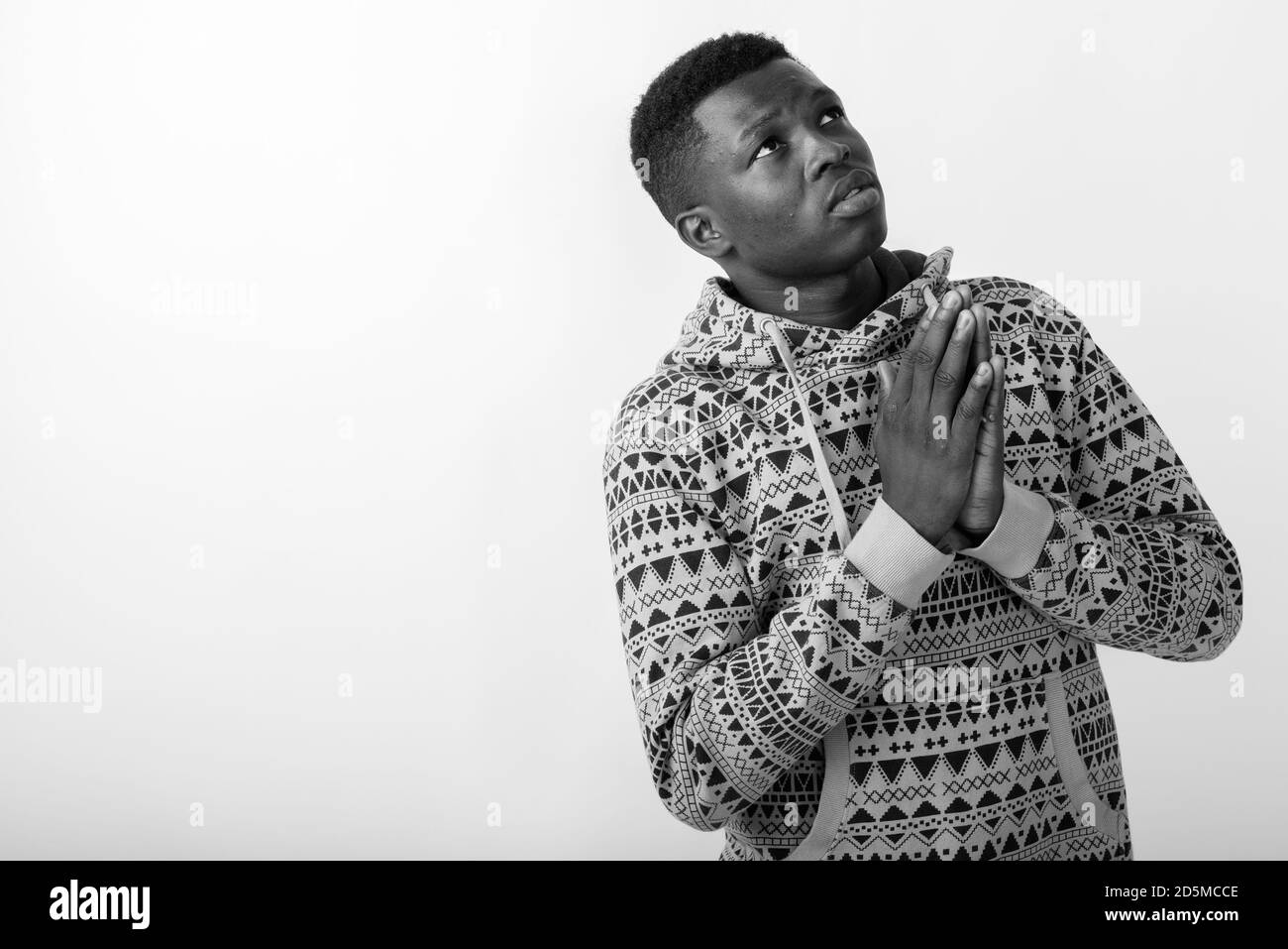 Studio di un giovane uomo nero africano che prega mentre si pensa e guardando in alto Foto Stock