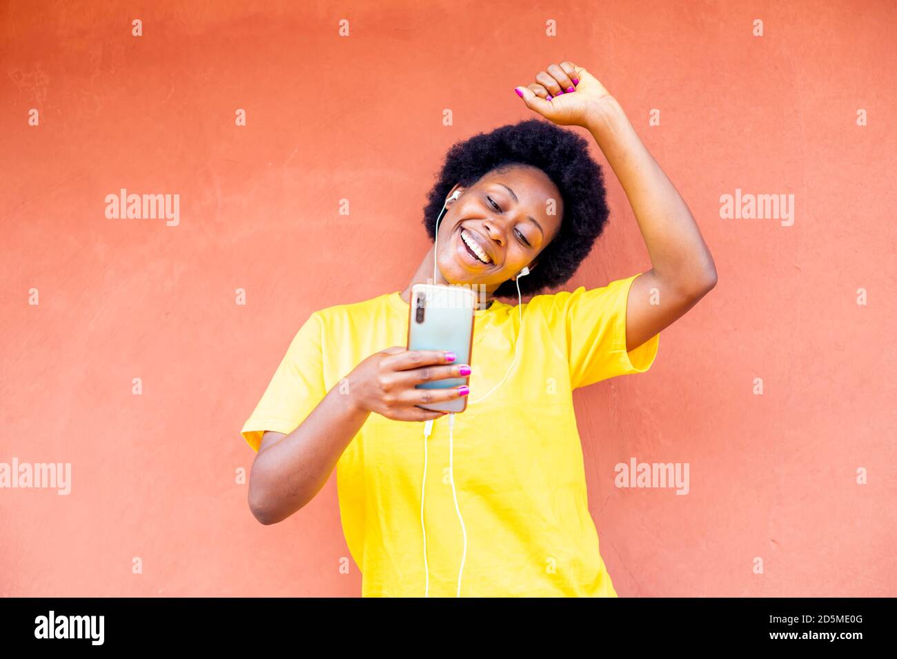 Foto autentica di un giovane millennial nero africano che si diverte utilizzo del telefono cellulare per l'ascolto di musica online Foto Stock