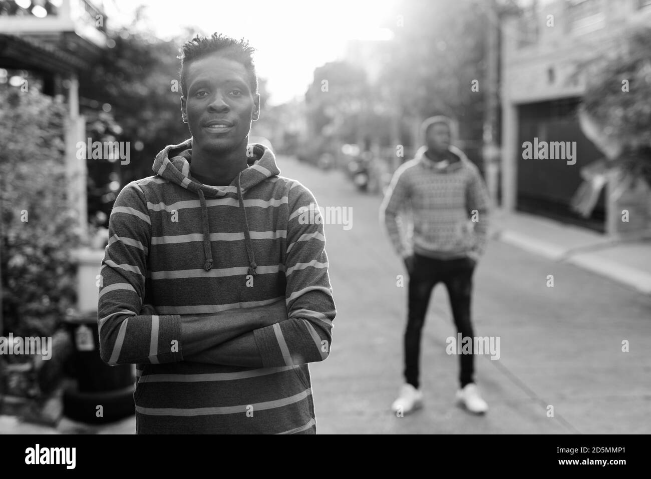 Giovane uomo africano nero sottile con le braccia incrociate e giovani Uomo nero africano sulla schiena all'aperto Foto Stock