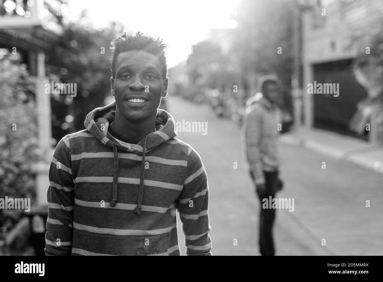 Giovani felici slim Africano nero uomo sorridente con il giovane nero africano sul retro all'esterno Foto Stock