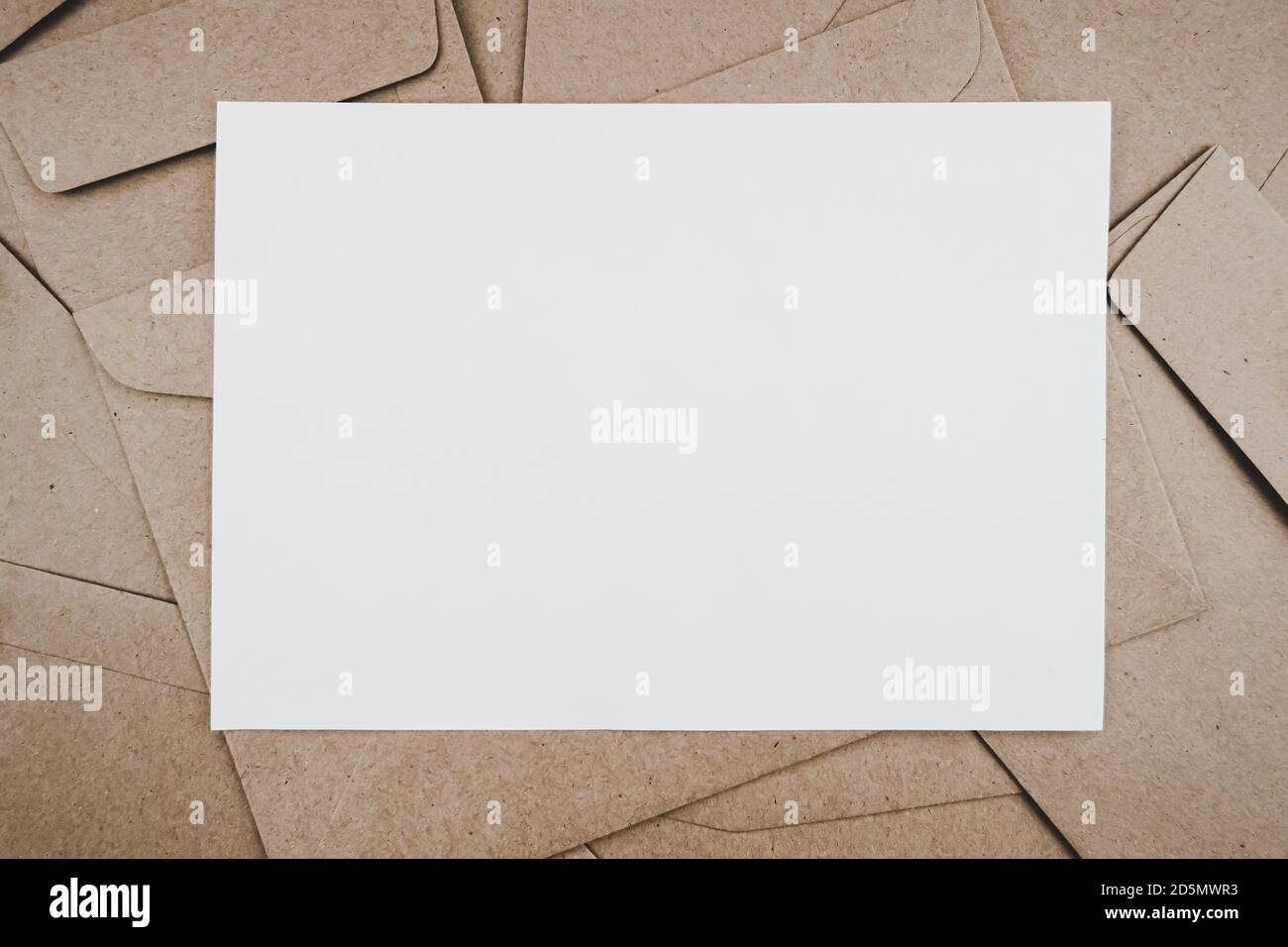 Vista dall'alto della busta di carta marrone con carta bianca. Disposizione piatta di molte buste di carta marrone sovrapposte. Stile minimalista. Foto Stock