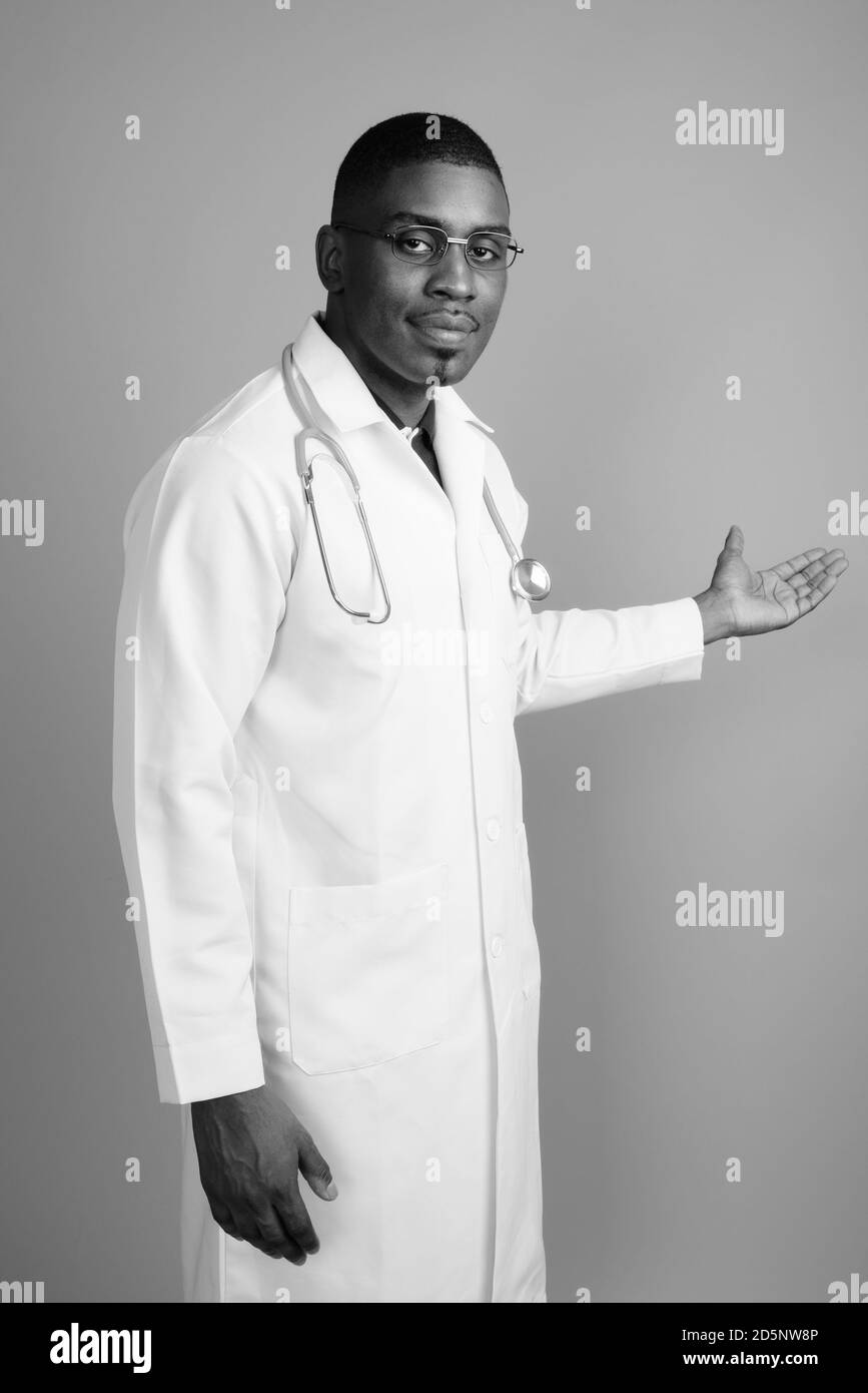 Bel giovane uomo africano medico contro uno sfondo grigio Foto Stock