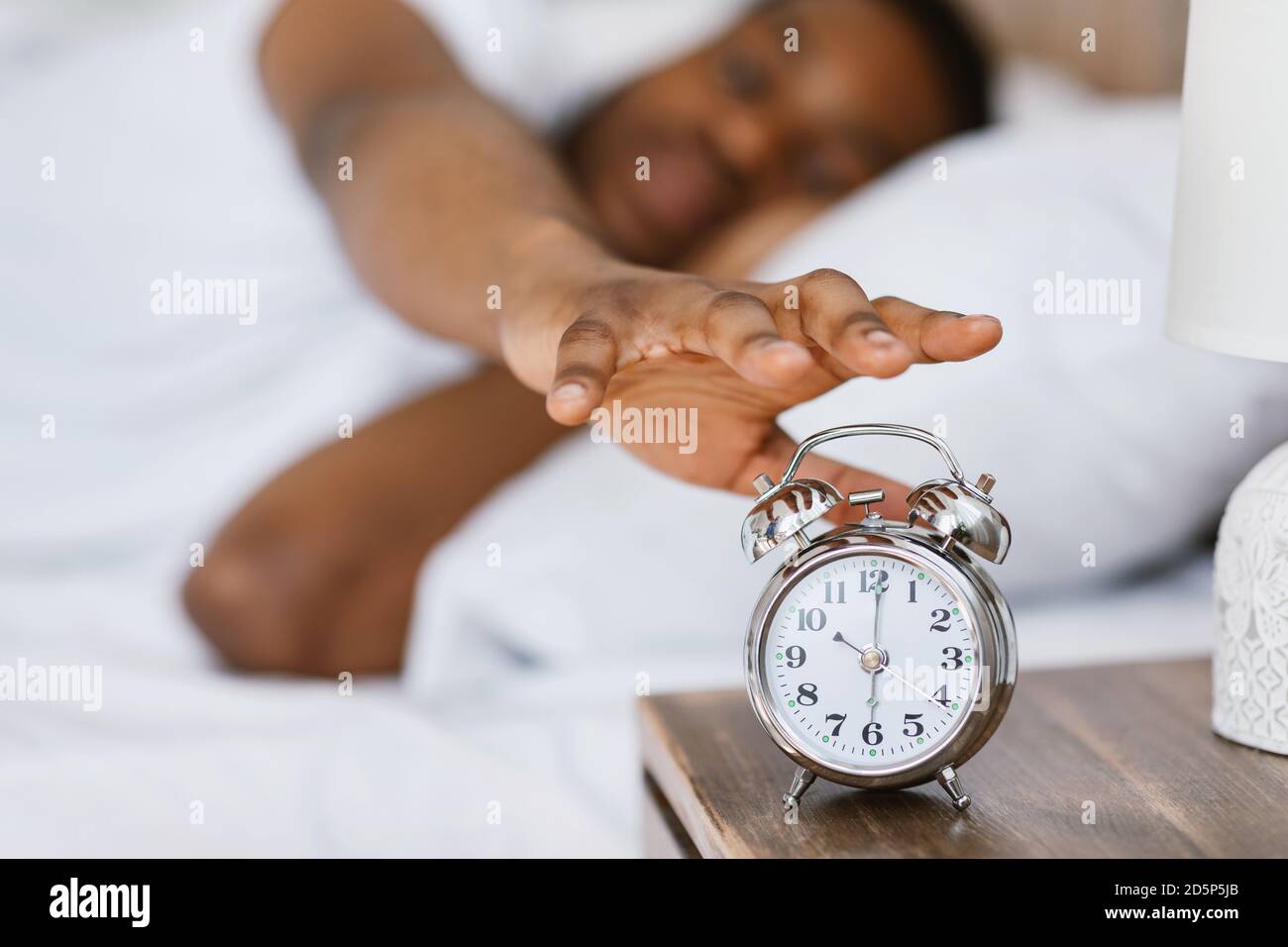 Guy africano risveglio spegnere sveglia sdraiata nel letto Foto Stock
