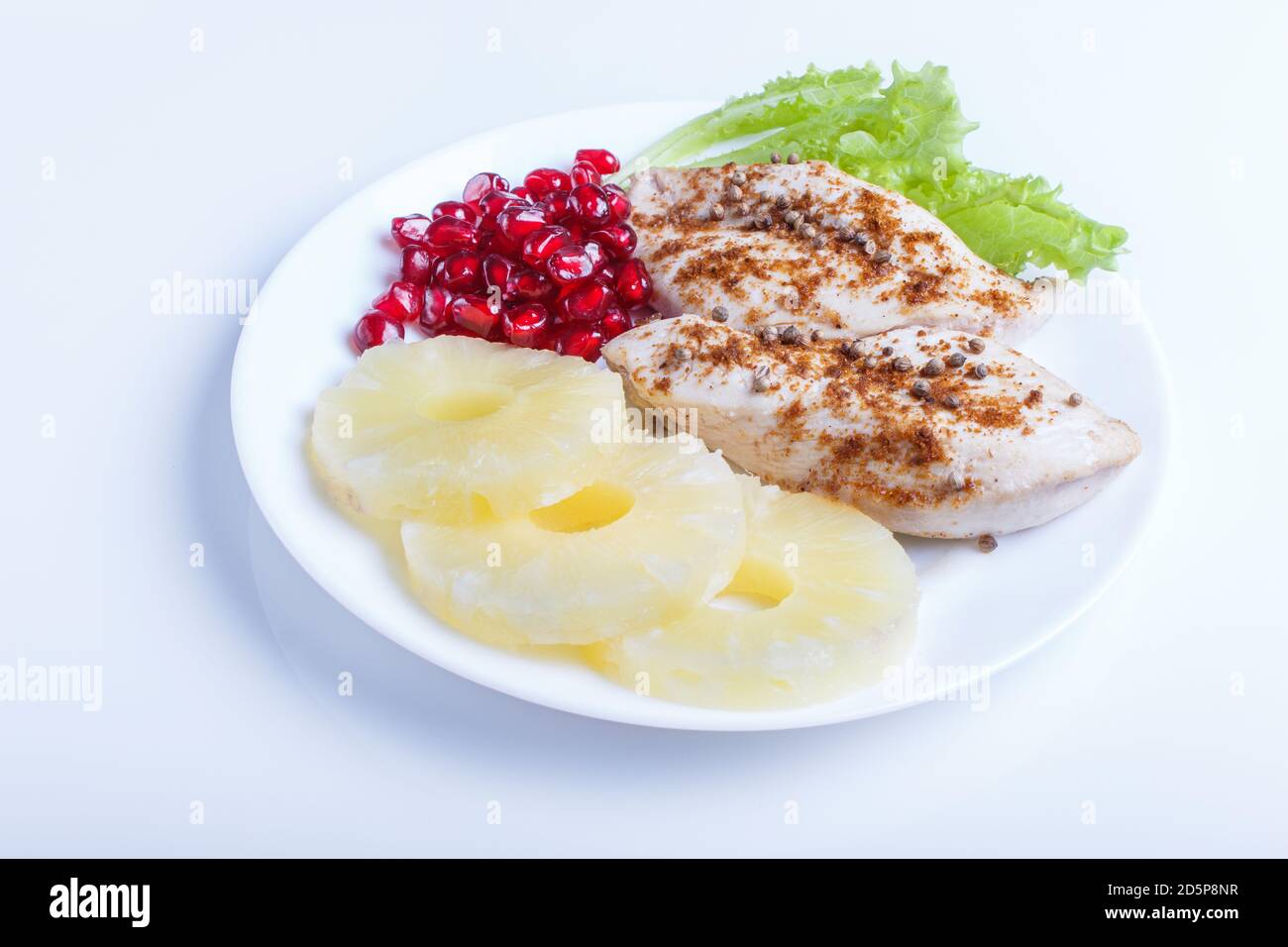 Filetti di pollo fritti con lattuga, ananas e semi di melograno isolati su sfondo bianco, primo piano. Foto Stock