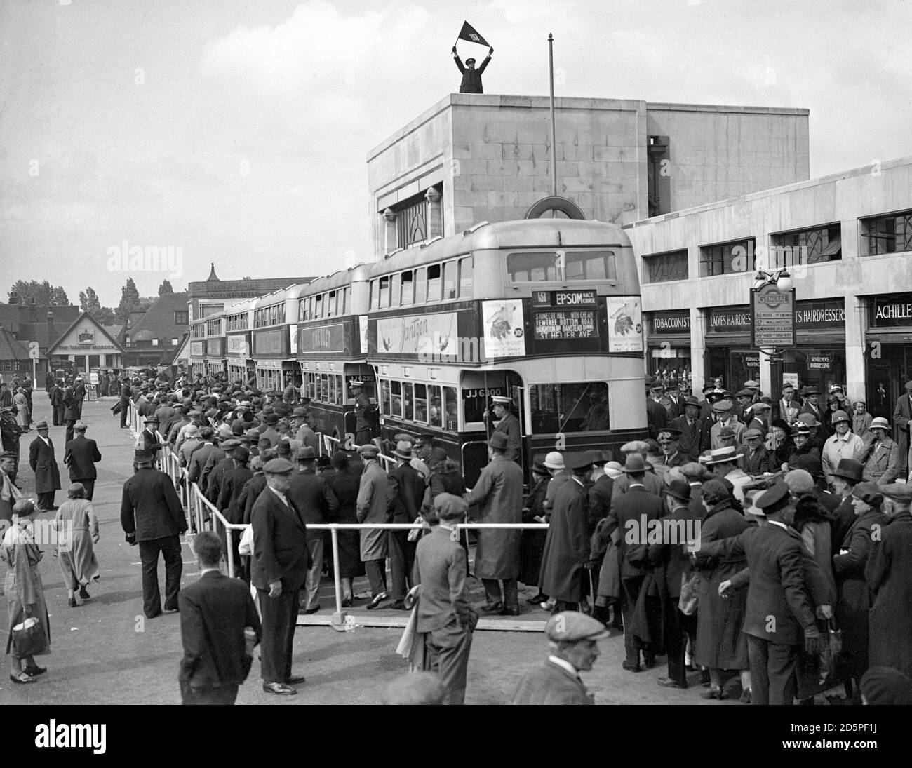 Un regolatore del traffico funziona dalla cima della stazione della metropolitana di Morden mentre la folla lascia l'Epsom Derby. Foto Stock