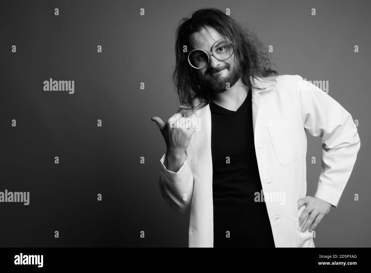 Giovane uomo barbuto medico contro uno sfondo grigio Foto Stock