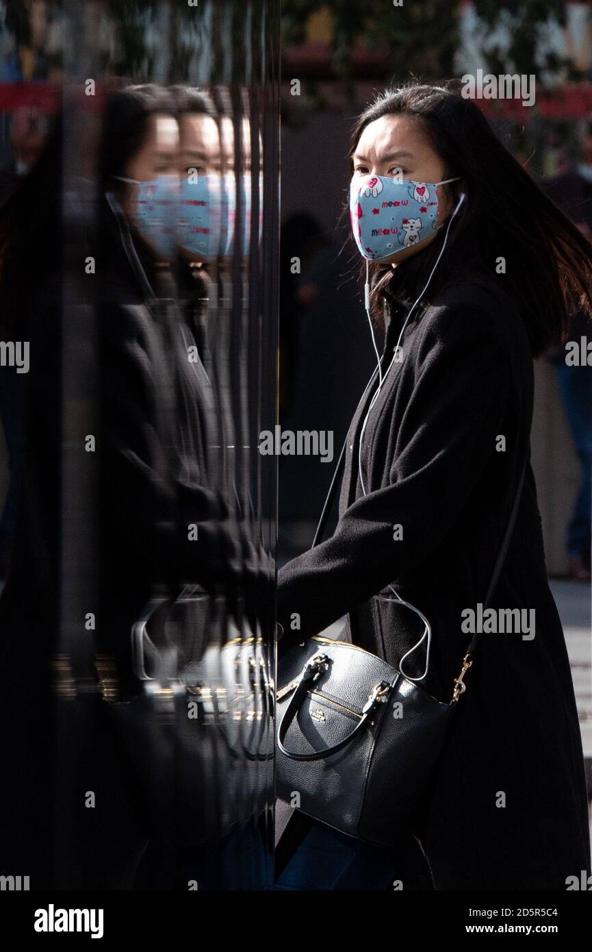 Una donna che indossa una maschera protettiva nel centro di Londra, dopo che il primo ministro Boris Johnson ha stabilito un nuovo sistema a tre livelli di allarme per l'Inghilterra a seguito di casi di coronavirus in aumento e ricoveri ospedalieri. Foto Stock