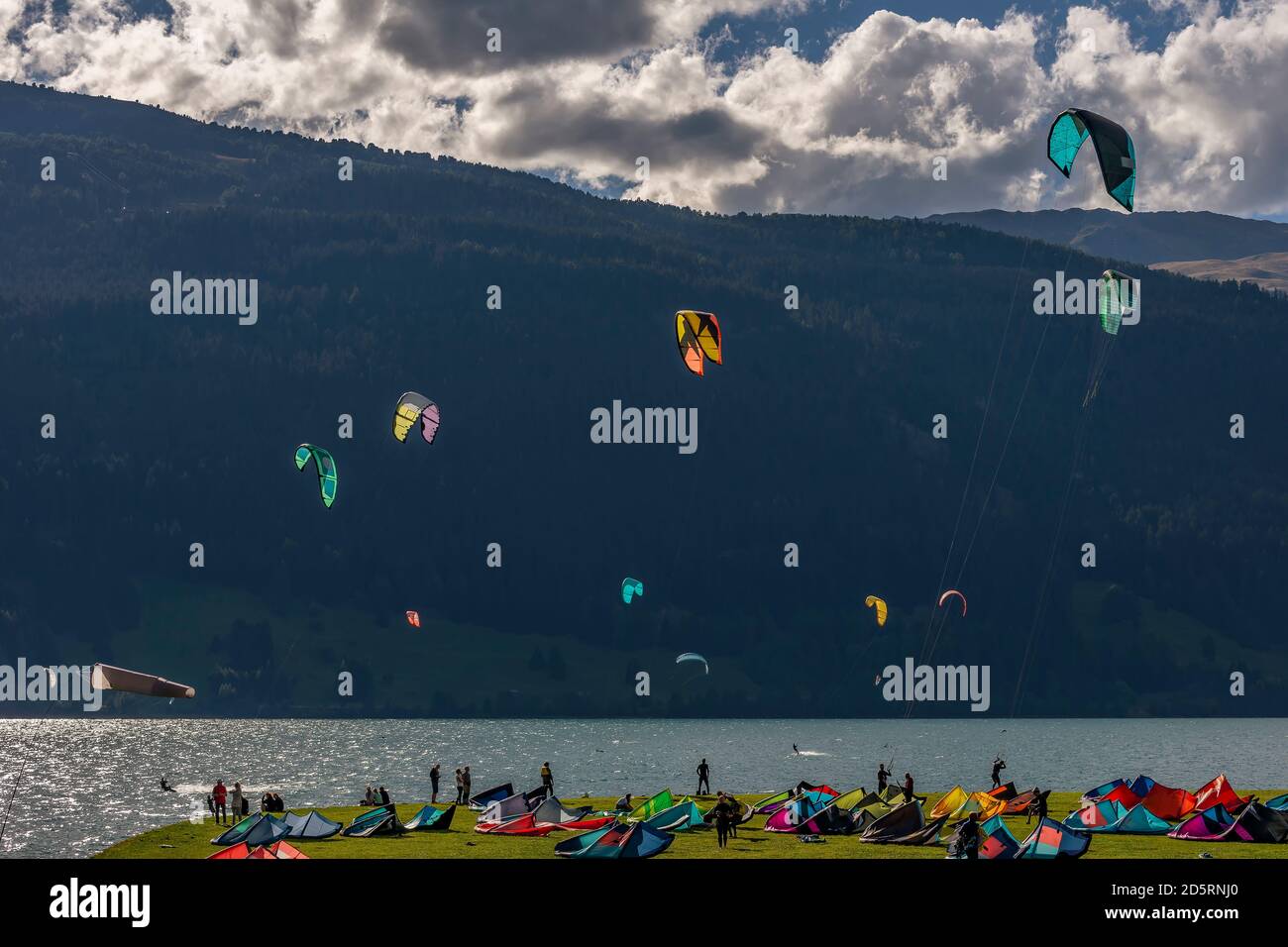 Diversi kite surfisti in azione sul Lago di Resia hanno girato contro la luce a Curon Venosta, Alto Adige, Italia Foto Stock