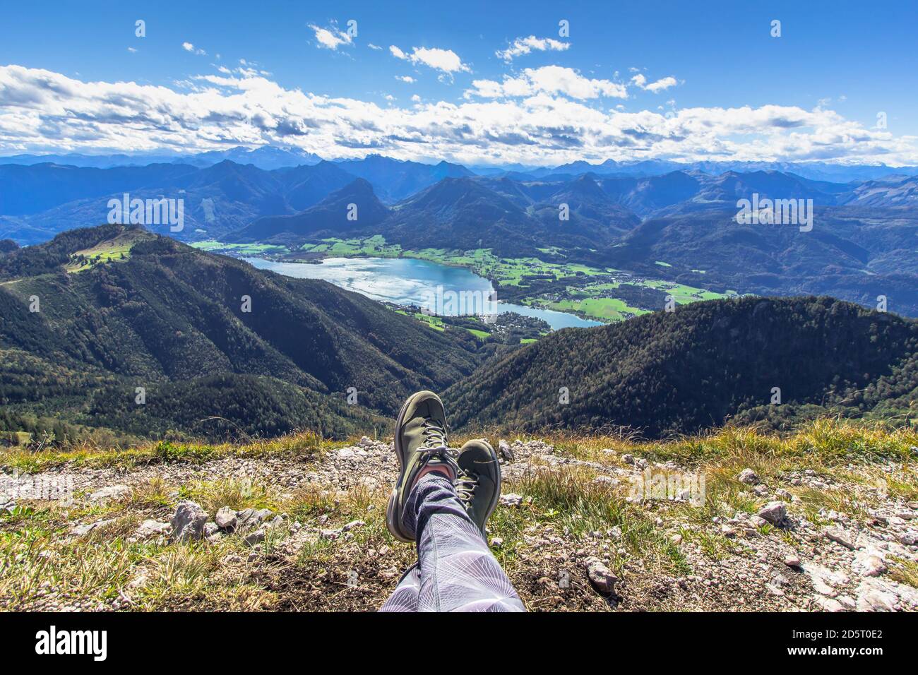 Gambe di viaggiatori seduti su un'alta montagna. Concetto di libertà di viaggio. Scarpe da trekking contro un bellissimo paesaggio. Meraviglioso mozzafiato m Foto Stock