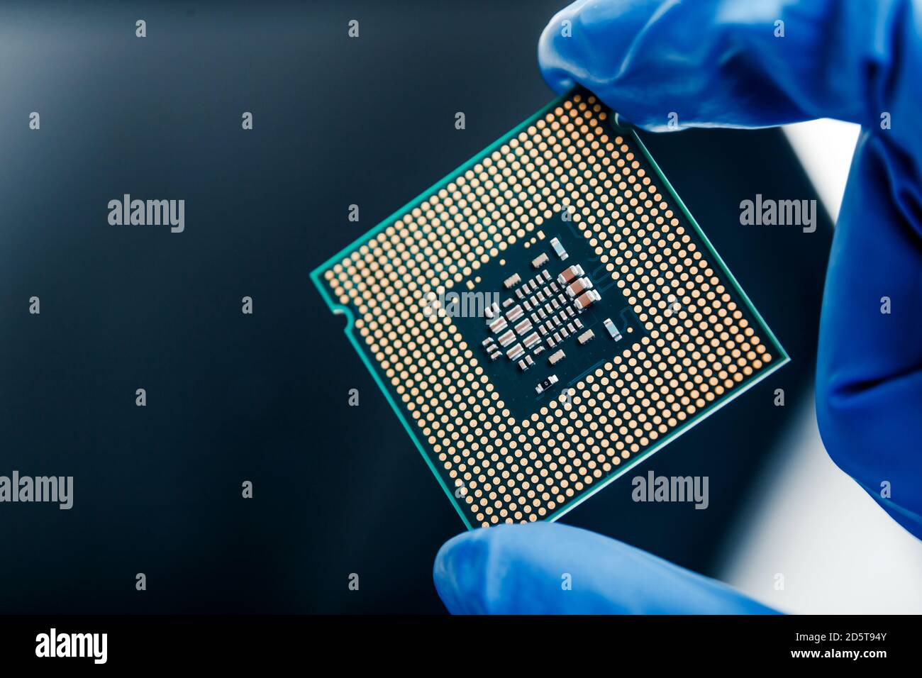 Vista ravvicinata su un nuovo microchip semiconduttore in mano oscura di computer scientist. Tecnologia moderna e sviluppo hardware Foto Stock