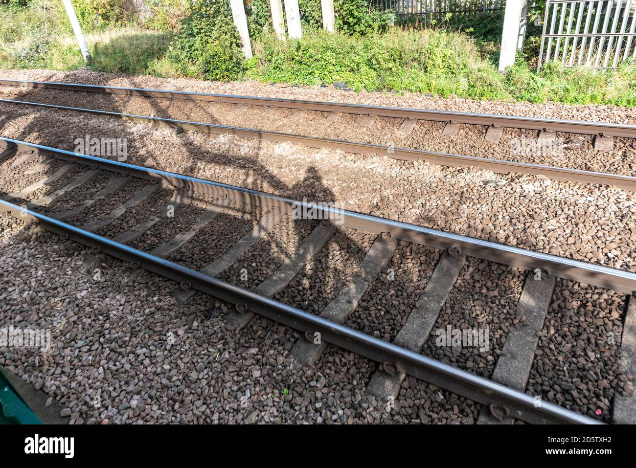 Ombra di un trenino spotter su un ponte pedonale sulla C2C Fenchurch Street verso Southend line a Westcliff on Sea, Essex, Regno Unito. Foto Stock