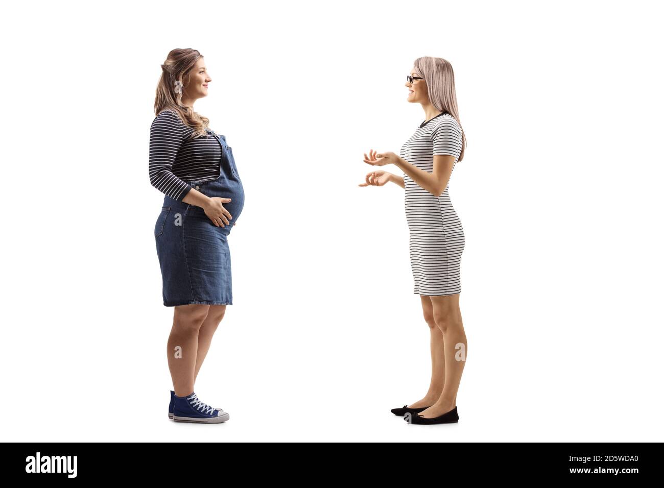 Foto di profilo a lunghezza intera di una donna bionda che parla con la sua amica incinta isolato su sfondo bianco Foto Stock