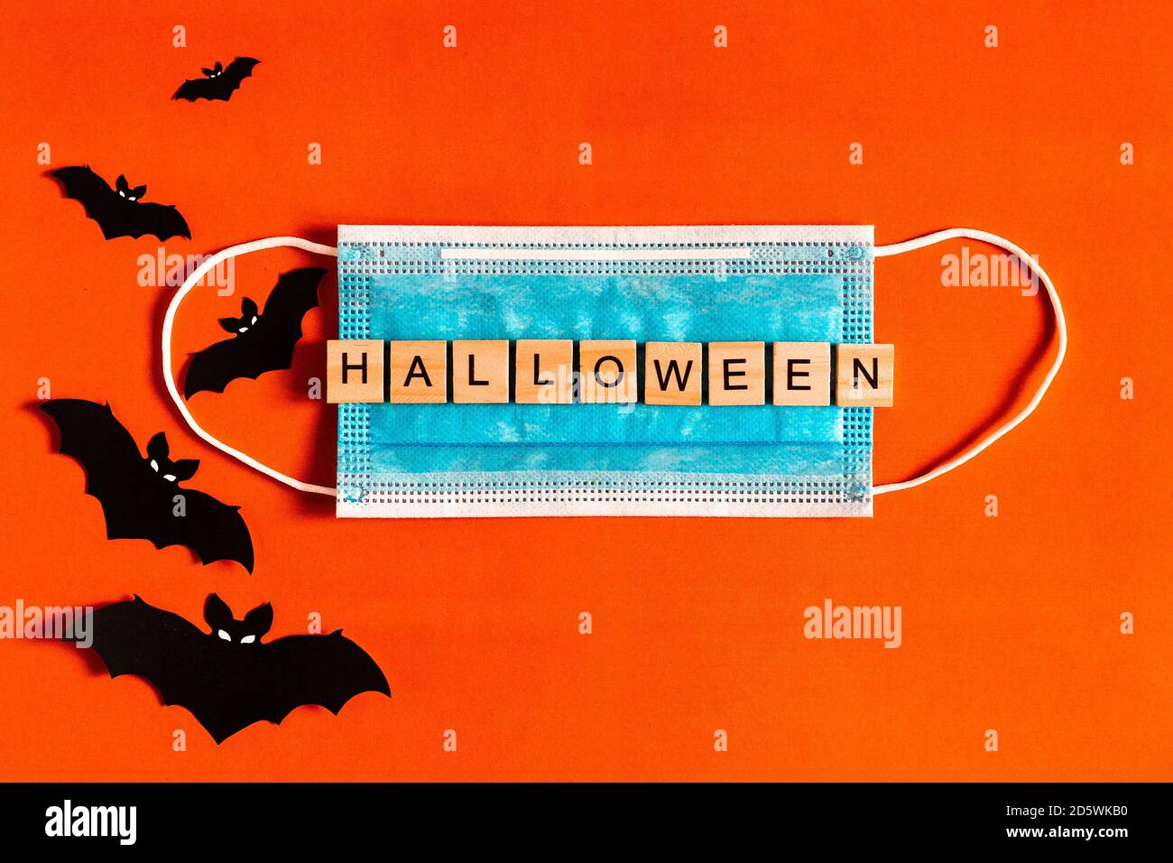 Scritta Halloween su una maschera medica protettiva su sfondo nero con silhouette di pipistrelli in carta nera, Halloween 2020 in una nuova realtà Foto Stock