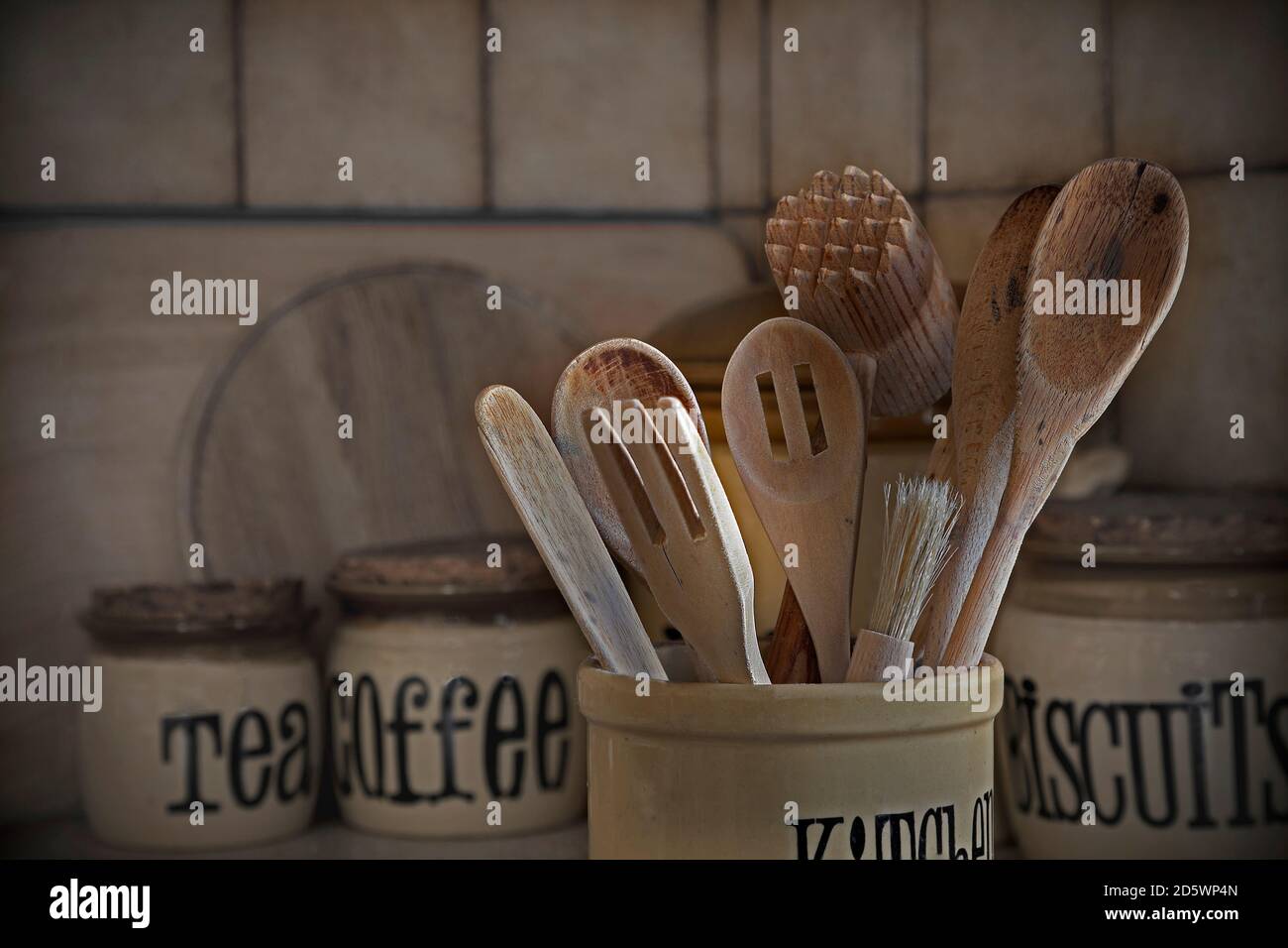 Utensili da cucina in legno e vasetti di stoccaggio retrò e ben utilizzati in cucina, con closeup in luce naturale Foto Stock