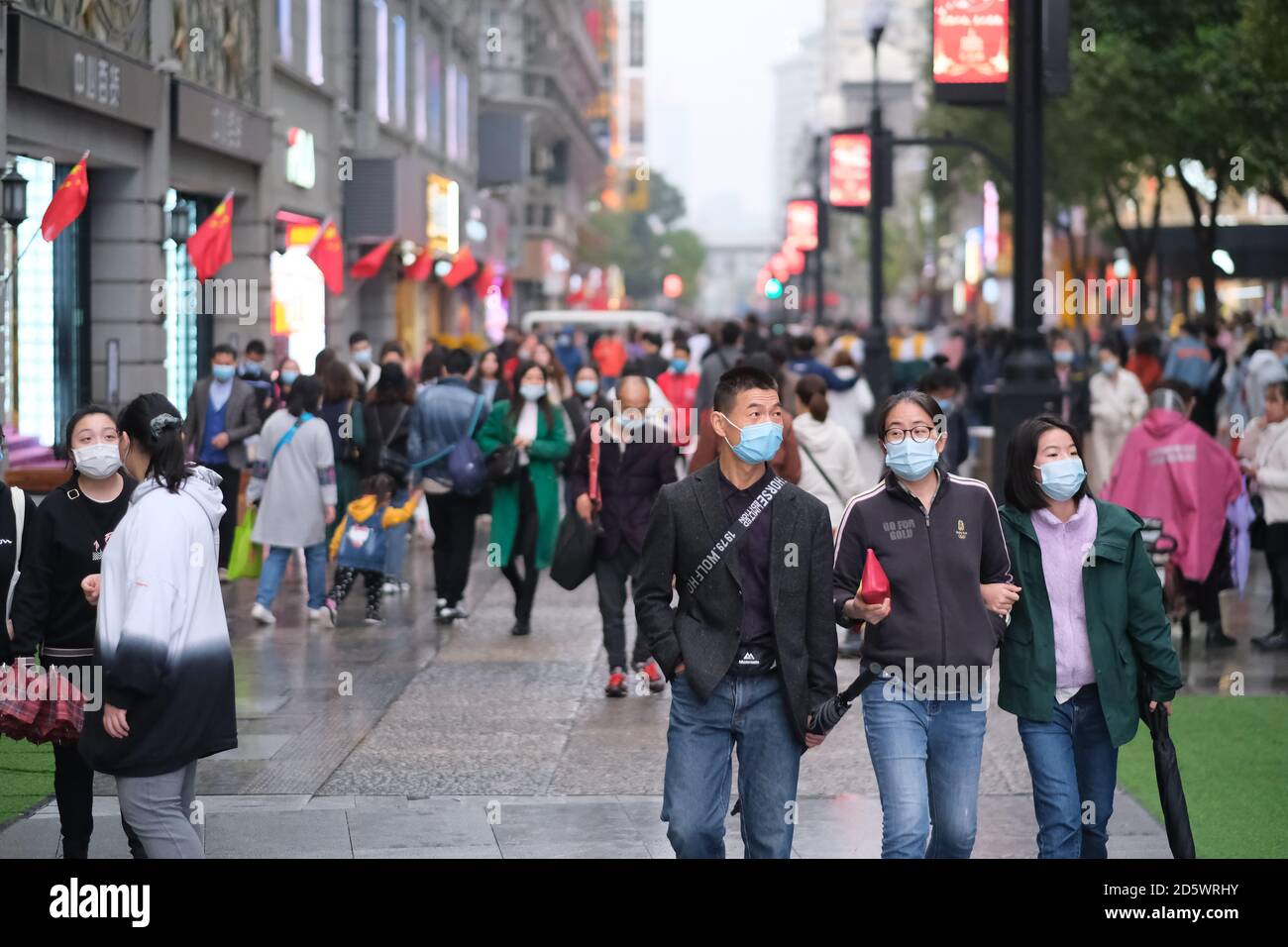 Persone in maschera di faccia per prevenire il coronavirus, a piedi su Jianghan Road. Jianghan Road è una famosa strada commerciale di Wuhan Foto Stock