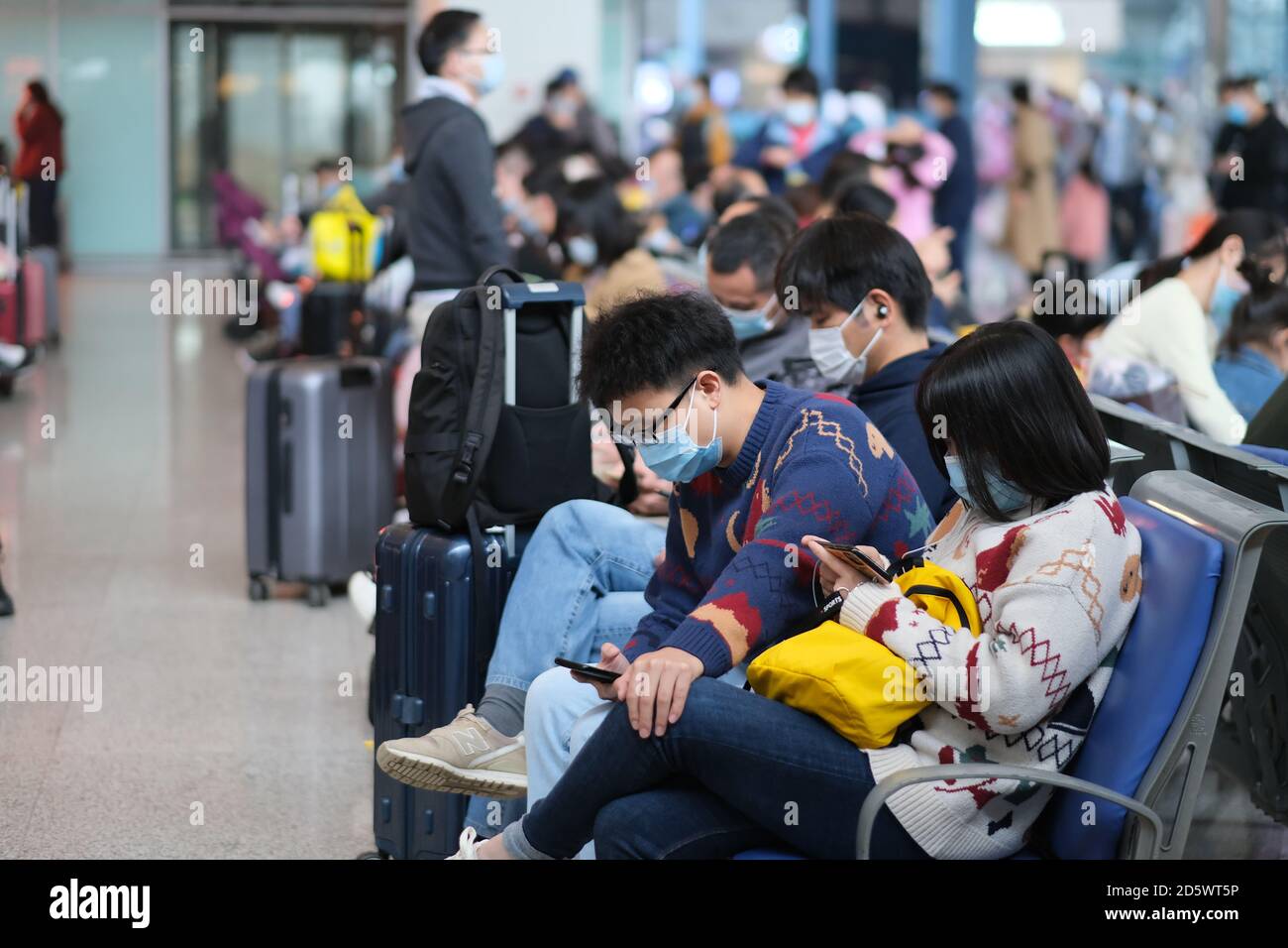 Viaggiatori in maschera per prevenire il coronavirus, in attesa nella stazione ferroviaria di Wuhan Foto Stock