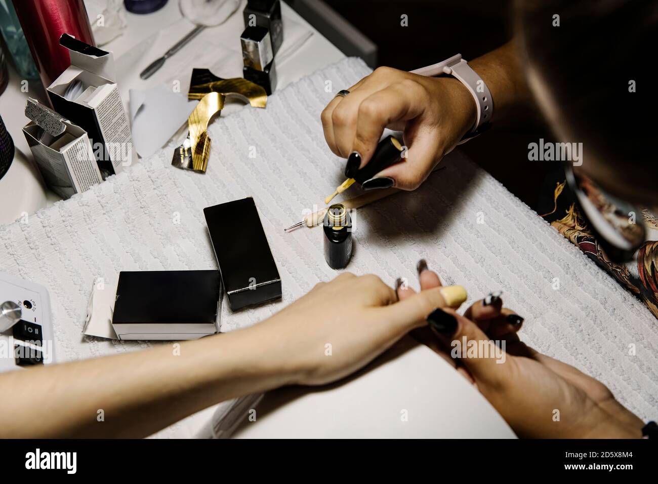 Anonimo artista del chiodo che applica lo smalto del chiodo mentre facendo manicure a. cliente Foto Stock