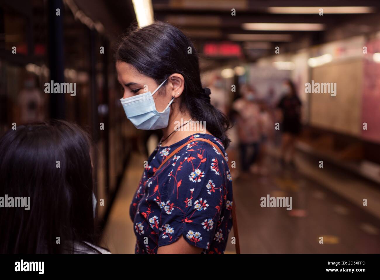 Giovane donna brunetta che indossa la maschera sulla stazione della metropolitana. Foto Stock