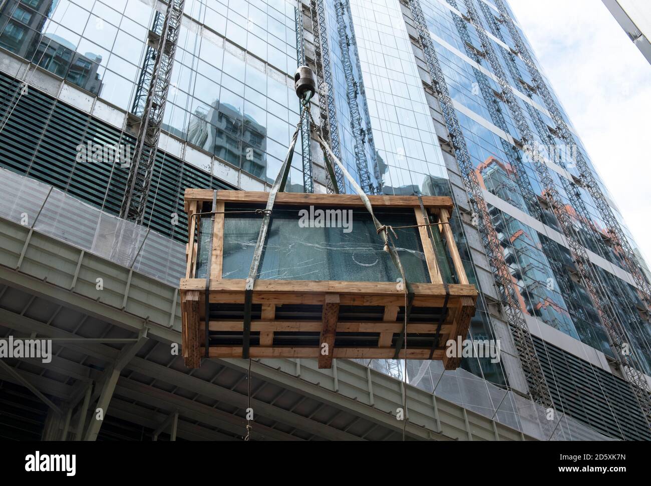 Hong Kong, Cina: 01 ago, 2020. I pannelli di vetro per edifici vengono sollevati in posizione durante i lavori di costruzione. Alamy Stock Image/Jayne Russell Foto Stock