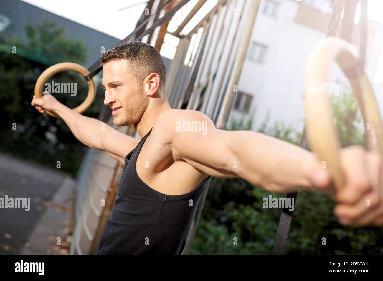 Muscly giovane formazione su anelli di ginnastica Foto Stock