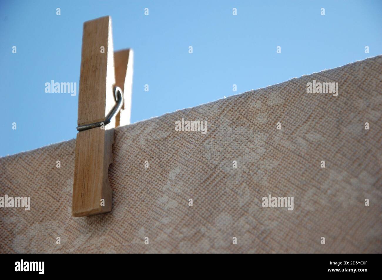 una spilla appesa un panno da tavolo su un filo e cielo blu sopra. asciugandosi al sole Foto Stock