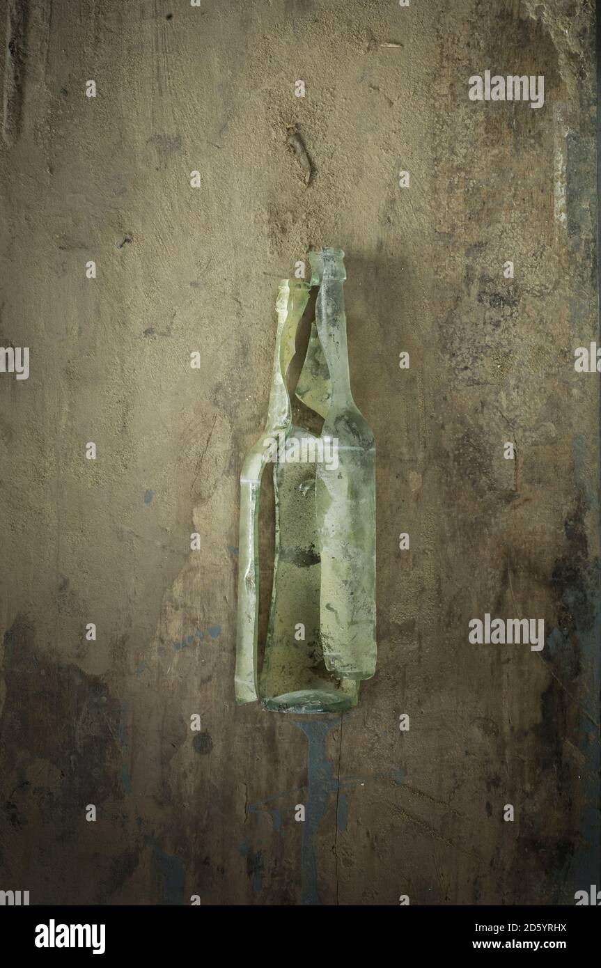 Vecchia bottiglia di vetro rotta su legno Foto Stock