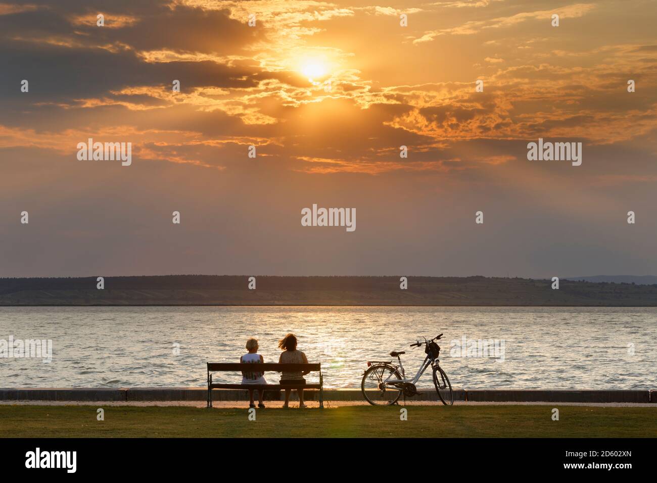 Austria, Burgenland, Illmitz, lago di Neusiedl, Gente seduta sul banco al tramonto Foto Stock