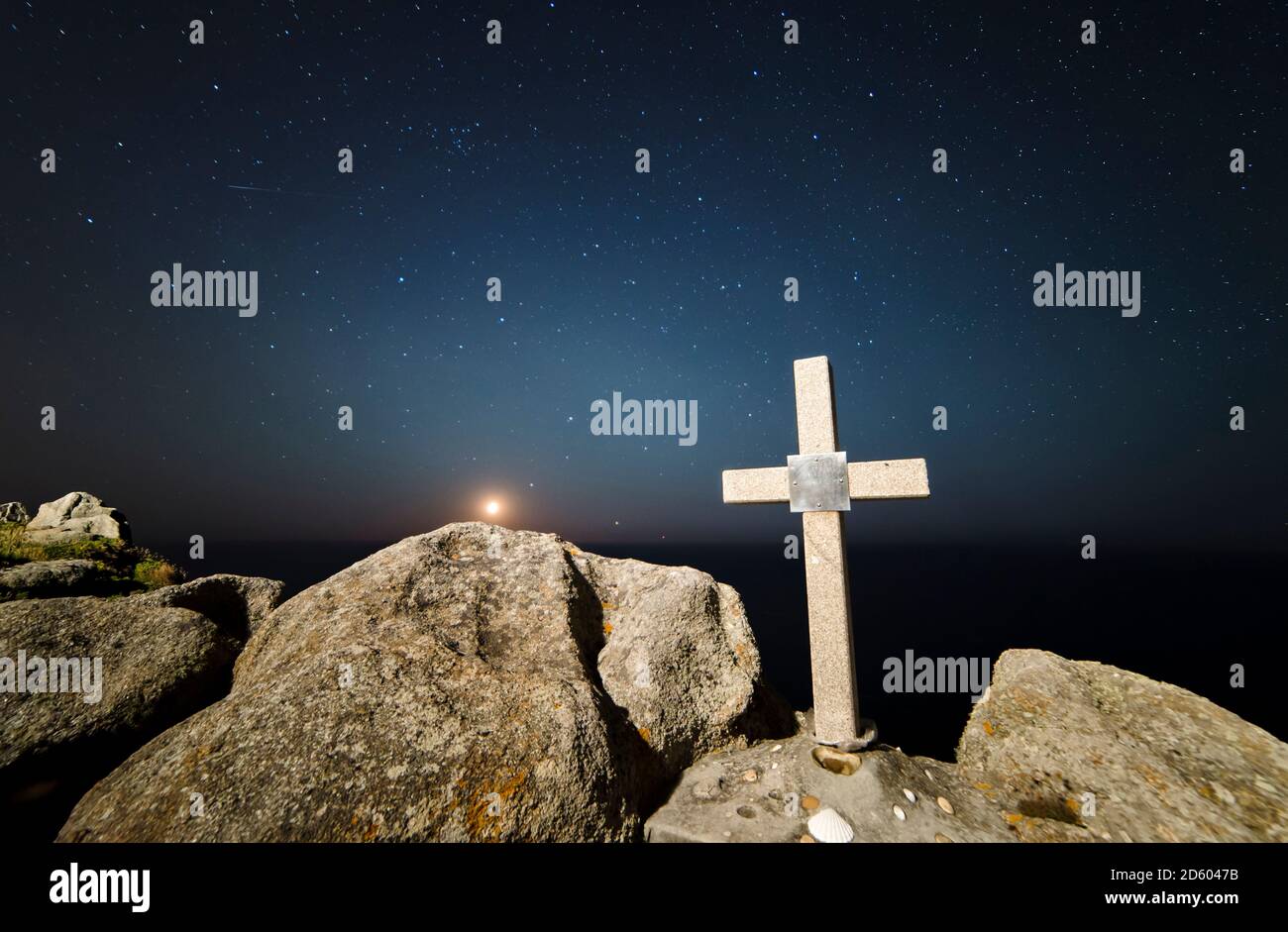 Spagna Galizia, Ferrol, calare della luna in un luogo della costa della Galizia con una croce di pietra in primo piano Foto Stock