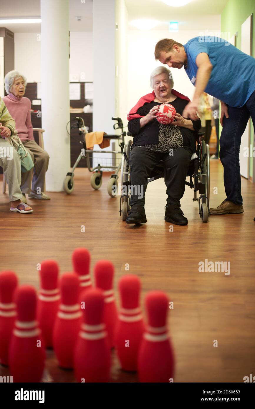Infermiera geriatrica parlando di età senior demented donna con sfere di schiuma in una casa di cura Foto Stock