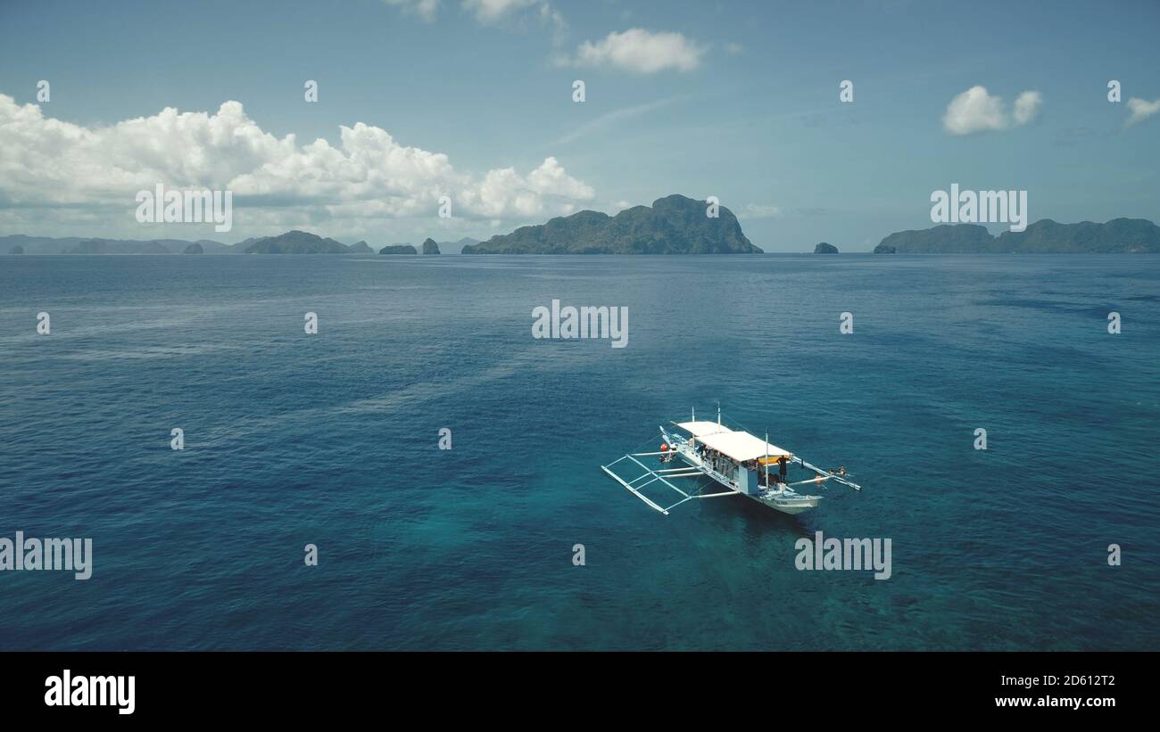 Antenna tropicale dell'oceano: Barche, navi, yacht in acque blu. Serena baia di mare a scogliera con navi. Paesaggio dell'isola di montagna nella foresta verde. Luce cinematografica soffusa del paesaggio rilassante della vacanza estiva Foto Stock