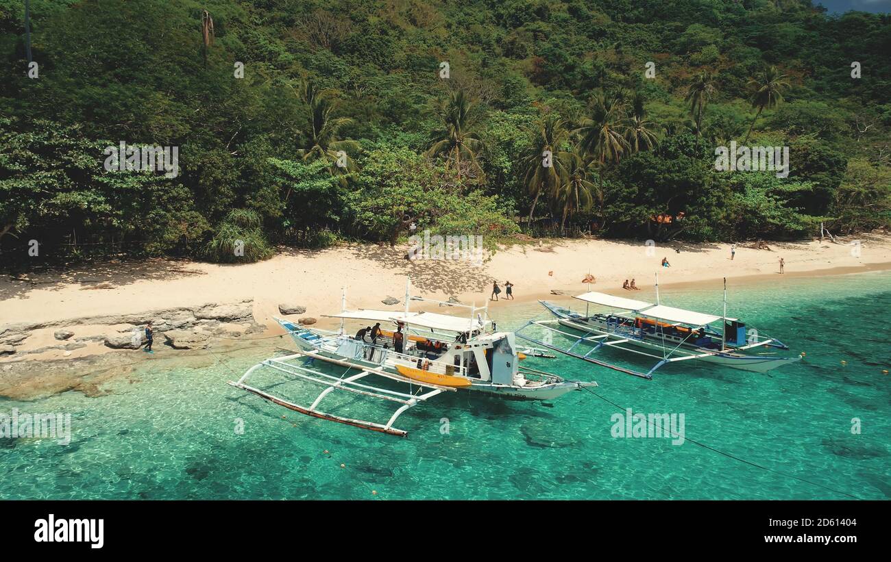Mare sereno con navi al golfo di mare di El Nido Isole, Filippine, Asia. Scogliera con barche da passeggeri vista aerea della baia dell'oceano. Verde foresta tropicale sulla riva rocciosa della spiaggia di sabbia. Foto Stock
