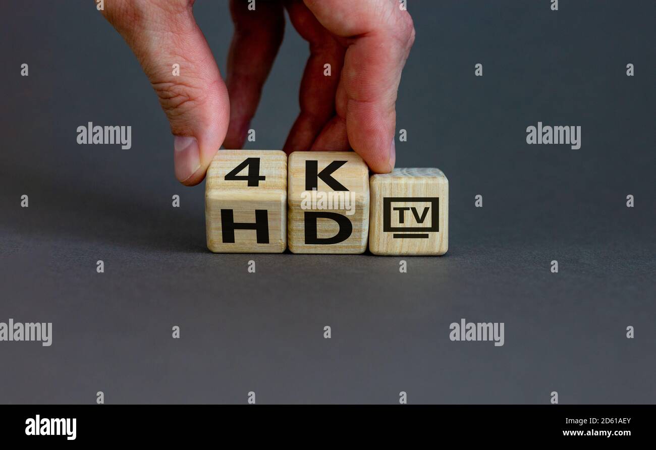 Simbolo del passaggio da TV HD a TV 4K. Mano maschio. Splendido sfondo grigio, spazio per la copia. Foto Stock