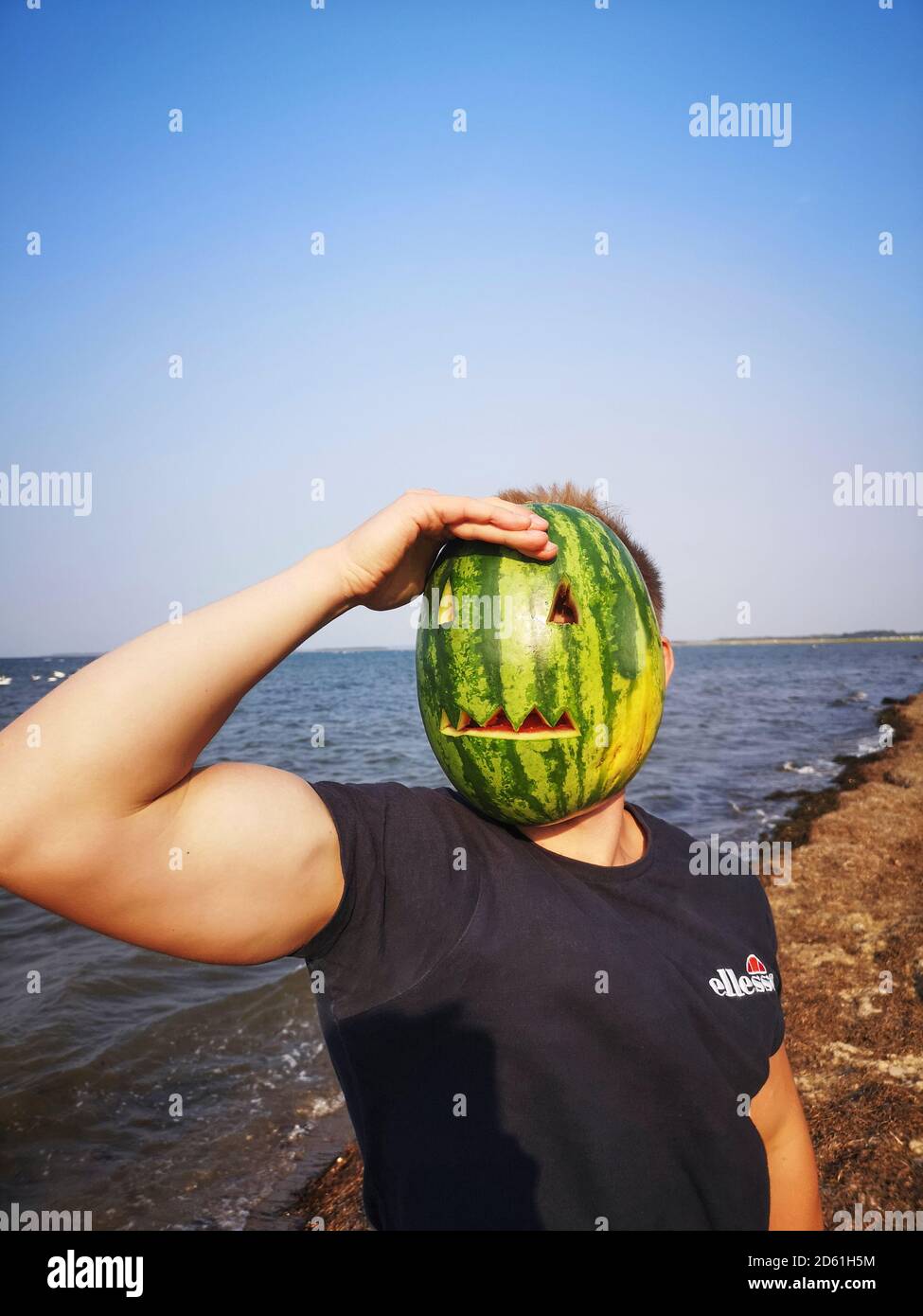 Poel, Germania - 16 settembre 2020: Foto di un giovane che non può essere riconosciuto perché sta tenendo una maschera scolpita da un angurello di fronte al hi Foto Stock