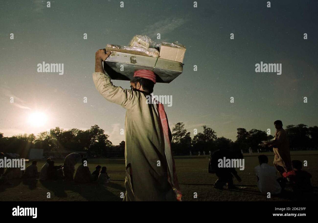 Un venditore pakistano vaga intorno alla folla che vende le sue merci Mentre l'Inghilterra gioca un Pakistan seleziona XI Foto Stock