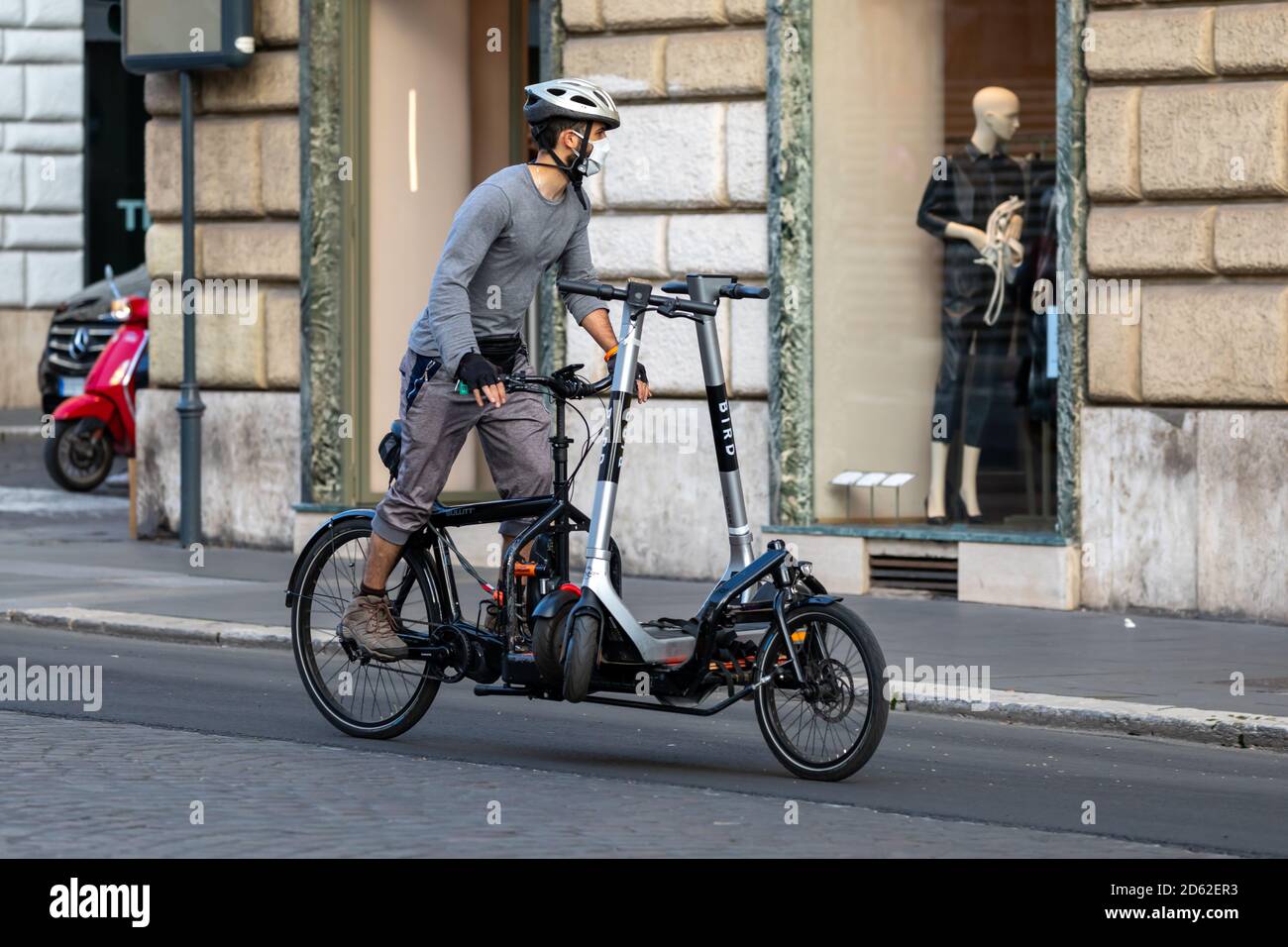 Roma, Italia - 10 ottobre 2020: Il ragazzo responsabile della manutenzione degli scooter elettrici distribuiti per il noleggio in città, trasporta alcuni scooter su un sp Foto Stock