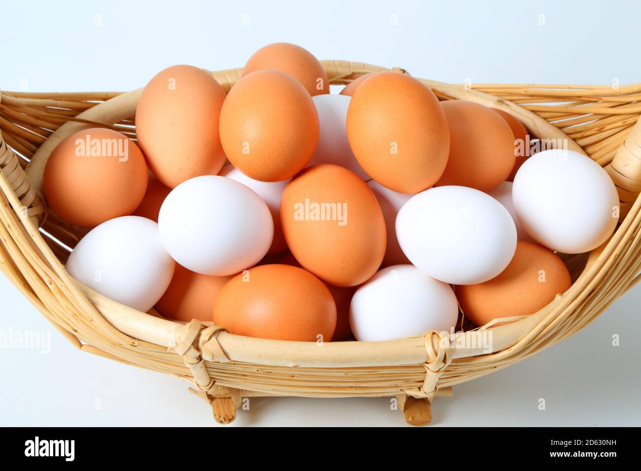 Uova fresche di colore marrone e bianco in cestino Foto Stock