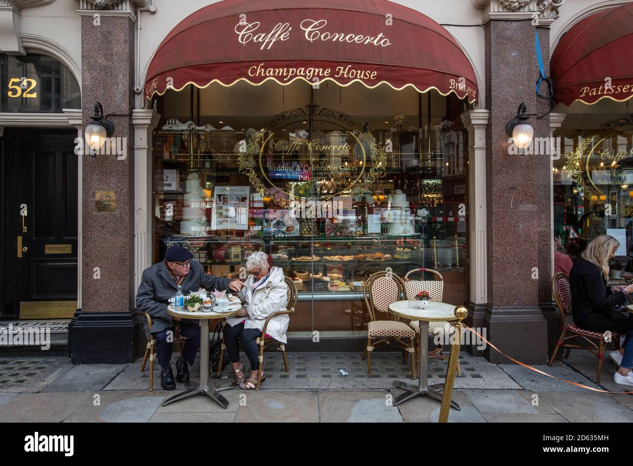 Una coppia anziana gusterà il tè pomeridiano mentre si siede all'esterno del caffe Concerto su Shaftesbury Avenue, cuore del West End di Londra, Inghilterra, Regno Unito Foto Stock